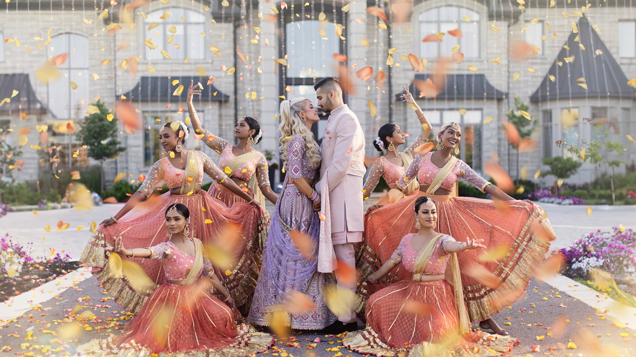 South Asian wedding couple surrounded by dancers and flower petals