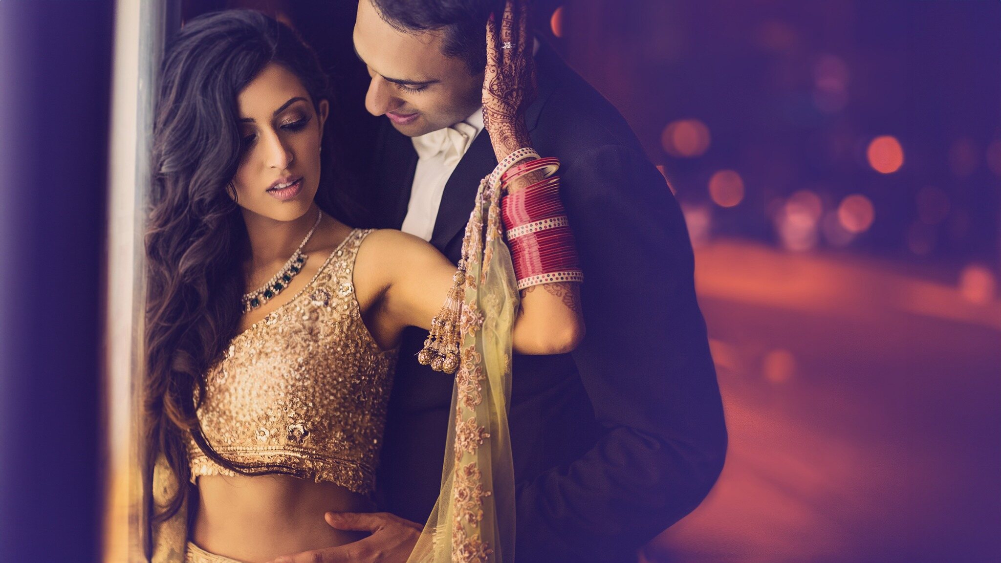 Couple photographed beneath colourful ambient lighting during an evening wedding portrait session