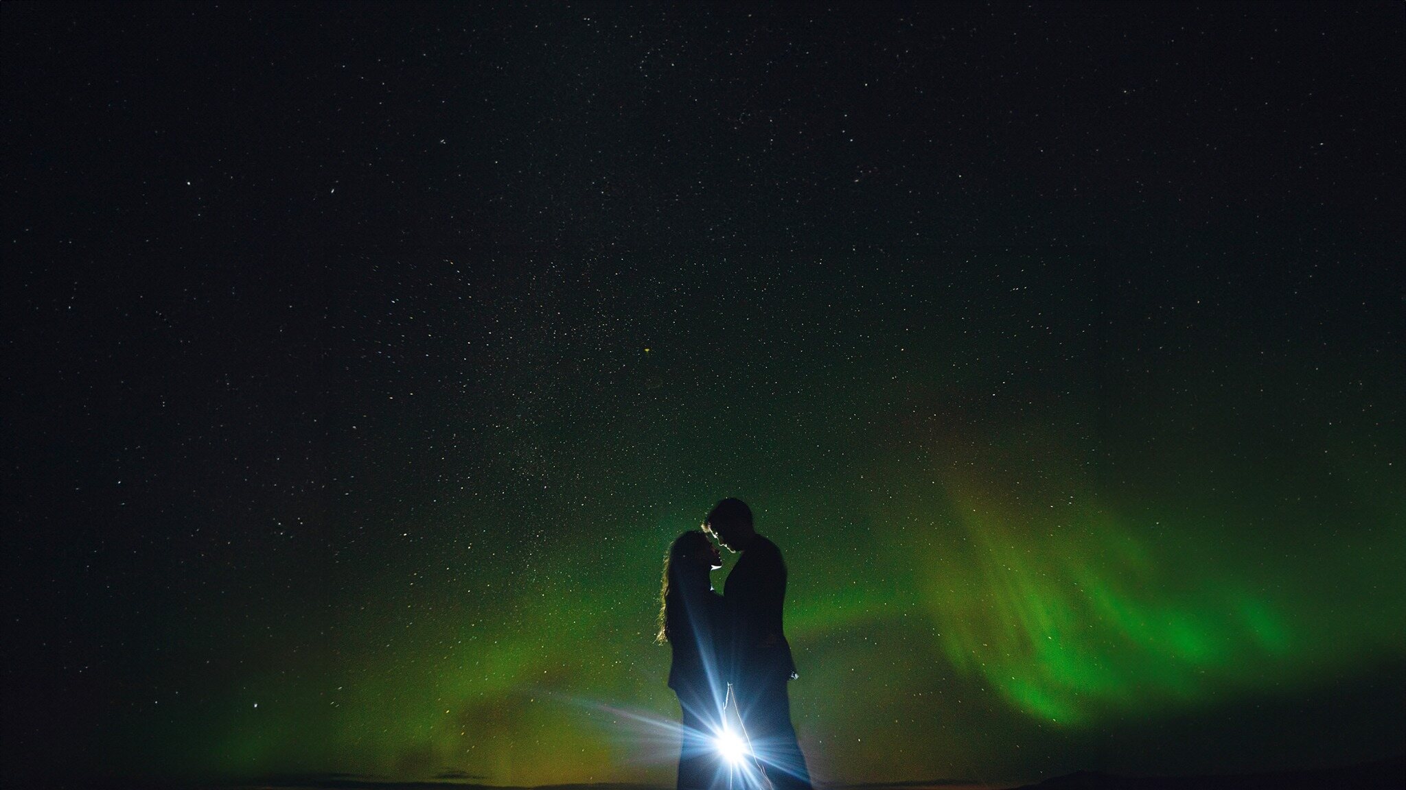 Couple silhouetted beneath the northern lights during an evening destination wedding portrait